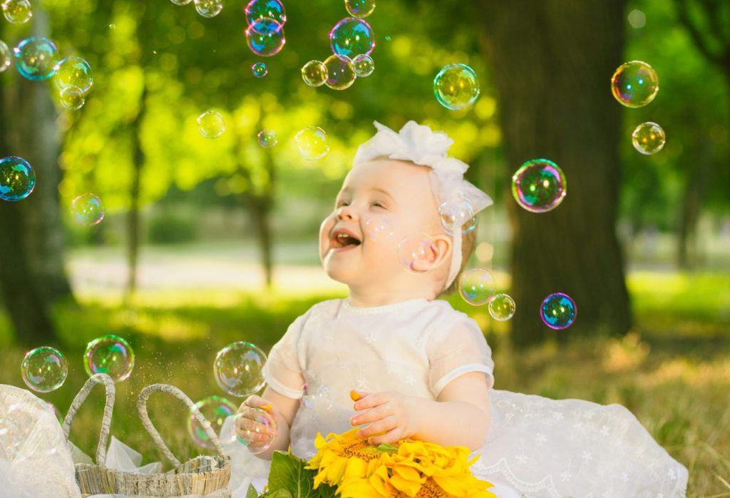 une petite fille en robe blanche assise dans l'herbe